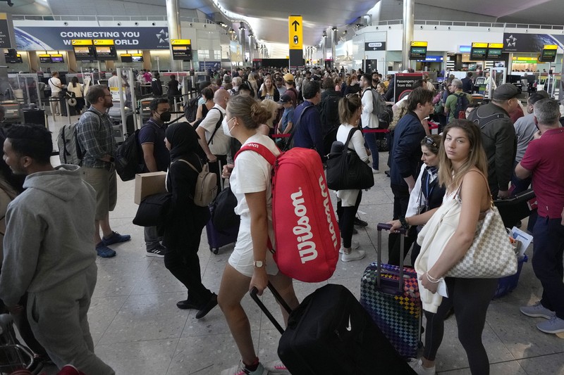 FILE - Travellers queue at security at Heathrow Airport in London, Wednesday, June 22, 2022. People face travelling disruption and long queues at airports amid the industry's ongoing staffing crisis. After two years of pandemic restrictions, travel demand is back with a vengeance but airlines and airports that slashed jobs during the depths of the COVID-19 crisis are struggling to keep up. With the busy summer tourism season underway in Europe, passengers are encountering chaotic scenes at airports, including lengthy delays, canceled flights and headaches over lost luggage. (AP Photo/Frank Augstein, File)