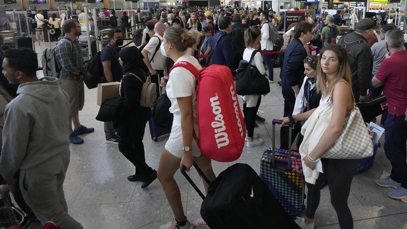 FILE - Travellers queue at security at Heathrow Airport in London, Wednesday, June 22, 2022. People face travelling disruption and long queues at airports amid the industry's ongoing staffing crisis. After two years of pandemic restrictions, travel demand is back with a vengeance but airlines and airports that slashed jobs during the depths of the COVID-19 crisis are struggling to keep up. With the busy summer tourism season underway in Europe, passengers are encountering chaotic scenes at airports, including lengthy delays, canceled flights and headaches over lost luggage. (AP Photo/Frank Augstein, File)