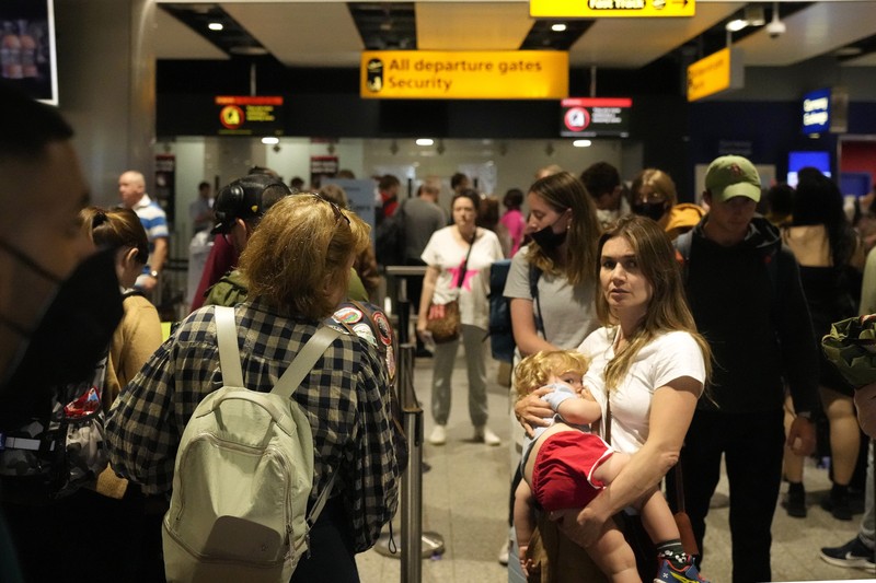 FILE - Travellers queue at security at Heathrow Airport in London, Wednesday, June 22, 2022. People face travelling disruption and long queues at airports amid the industry's ongoing staffing crisis. After two years of pandemic restrictions, travel demand is back with a vengeance but airlines and airports that slashed jobs during the depths of the COVID-19 crisis are struggling to keep up. With the busy summer tourism season underway in Europe, passengers are encountering chaotic scenes at airports, including lengthy delays, canceled flights and headaches over lost luggage. (AP Photo/Frank Augstein, File)
