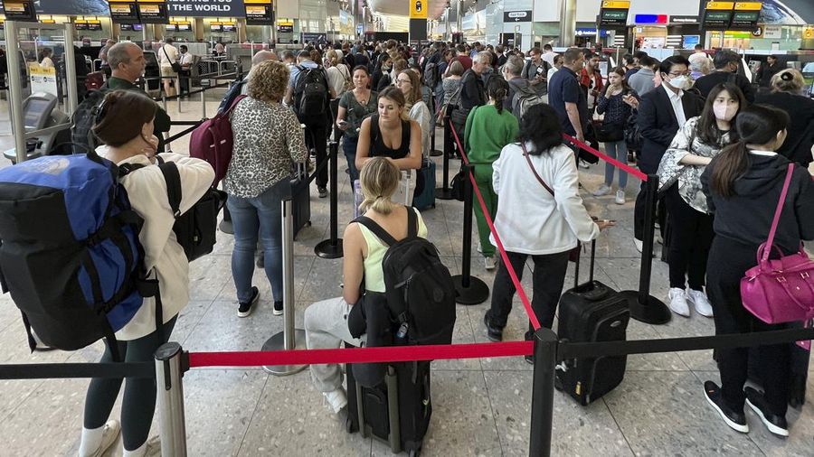 FILE - Travellers queue at security at Heathrow Airport in London, Wednesday, June 22, 2022. People face travelling disruption and long queues at airports amid the industry's ongoing staffing crisis. After two years of pandemic restrictions, travel demand is back with a vengeance but airlines and airports that slashed jobs during the depths of the COVID-19 crisis are struggling to keep up. With the busy summer tourism season underway in Europe, passengers are encountering chaotic scenes at airports, including lengthy delays, canceled flights and headaches over lost luggage. (AP Photo/Frank Augstein, File)