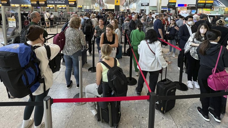 FILE - Travellers queue at security at Heathrow Airport in London, Wednesday, June 22, 2022. People face travelling disruption and long queues at airports amid the industry's ongoing staffing crisis. After two years of pandemic restrictions, travel demand is back with a vengeance but airlines and airports that slashed jobs during the depths of the COVID-19 crisis are struggling to keep up. With the busy summer tourism season underway in Europe, passengers are encountering chaotic scenes at airports, including lengthy delays, canceled flights and headaches over lost luggage. (AP Photo/Frank Augstein, File)