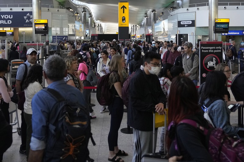 FILE - Travellers queue at security at Heathrow Airport in London, Wednesday, June 22, 2022. People face travelling disruption and long queues at airports amid the industry's ongoing staffing crisis. After two years of pandemic restrictions, travel demand is back with a vengeance but airlines and airports that slashed jobs during the depths of the COVID-19 crisis are struggling to keep up. With the busy summer tourism season underway in Europe, passengers are encountering chaotic scenes at airports, including lengthy delays, canceled flights and headaches over lost luggage. (AP Photo/Frank Augstein, File)