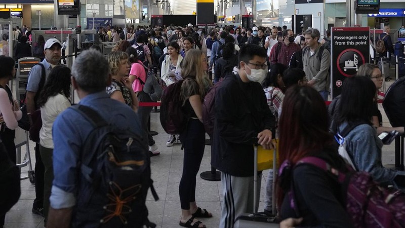 FILE - Travellers queue at security at Heathrow Airport in London, Wednesday, June 22, 2022. People face travelling disruption and long queues at airports amid the industry's ongoing staffing crisis. After two years of pandemic restrictions, travel demand is back with a vengeance but airlines and airports that slashed jobs during the depths of the COVID-19 crisis are struggling to keep up. With the busy summer tourism season underway in Europe, passengers are encountering chaotic scenes at airports, including lengthy delays, canceled flights and headaches over lost luggage. (AP Photo/Frank Augstein, File)