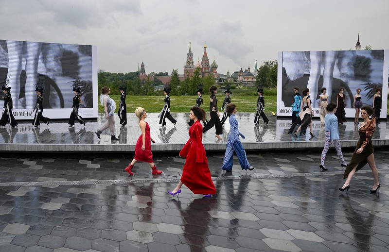 Russia Fashion Week Models display a collection by a group of Russian designers of the Moscow Art-Industrial Institute, during the Fashion Week at Zaryadye Park with the Spasskaya Tower and St. Basil's Cathedral on the left in background near Red Square in Moscow, Russia, Tuesday, June 21, 2022. (AP Photo/Alexander Zemlianichenko)