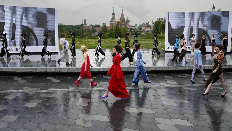 Models display a collection by a group of Russian designers of the Moscow Art-Industrial Institute, during the Fashion Week at Zaryadye Park with the Spasskaya Tower and St. Basil's Cathedral on the left in background near Red Square in Moscow, Russia, Tuesday, June 21, 2022. (AP Photo/Alexander Zemlianichenko)