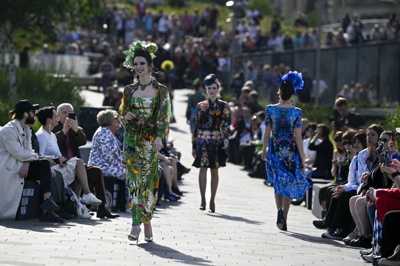 Russia Fashion Week Models display a collection by a group of Russian designers of the Moscow Art-Industrial Institute, during the Fashion Week at Zaryadye Park with the Spasskaya Tower and St. Basil's Cathedral on the left in background near Red Square in Moscow, Russia, Tuesday, June 21, 2022. (AP Photo/Alexander Zemlianichenko)