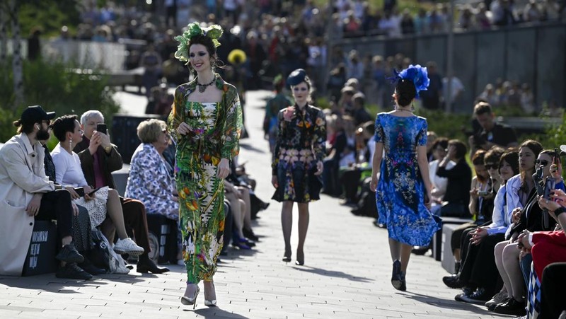 Models display a collection by a group of Russian designers of the Moscow Art-Industrial Institute, during the Fashion Week at Zaryadye Park with the Spasskaya Tower and St. Basil's Cathedral on the left in background near Red Square in Moscow, Russia, Tuesday, June 21, 2022. (AP Photo/Alexander Zemlianichenko)