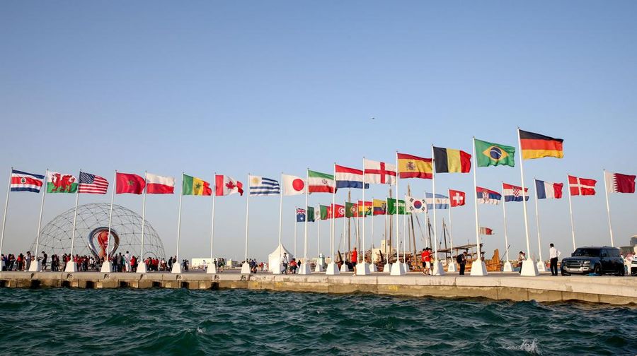 A general view shows flags of the qualified countries for the 2022 World Cup in the Qatari capital Doha during a flag-raising ceremony of the last remaining countries to qualify, on June 16, 2022. (Photo by Mustafa ABUMUNES / AFP) (Photo by MUSTAFA A