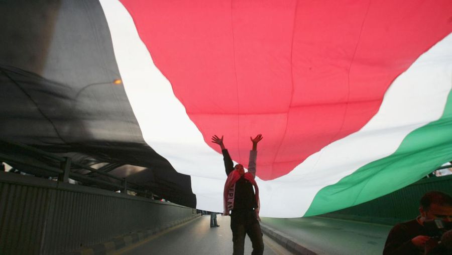 AMMAN, JORDAN- NOVEMBER 13: A Man jumps to touch a large Jordanian flag as Jordanians protest to commemorate the victims of November 9 suicide attacks on November 13, 2005 in downtown Amman, Jordan. According to Jordanian authorities a woman allegedly the wife of one of the suicide attackers has been taken into custody. The attacks left at least 60 dead and injured over one hundred people. (Photo by Salah Malkawi/ Getty Images)