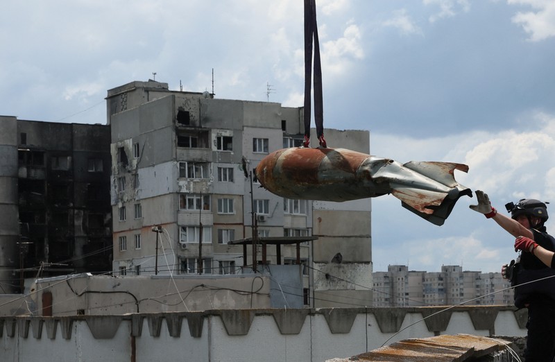 UKRAINE-CRISIS/ Members of a specialised team that defuses and removes explosives, bombs, mines and other munitions remove a defused 500kg bomb that did not detonate when it landed on an apartment building in March, in the Saltivka neighbourhood, as Russia’s attack on Ukraine continues, in Kharkiv, Ukraine, June 23, 2022. REUTERS/Leah Millis