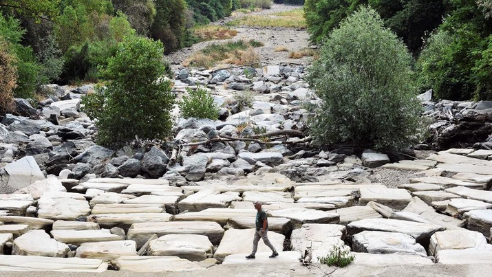 A man walks on the dry riverbed of Sangone river, a tributary of the Po river, which experiences its worst drought for 70 years, in Beinasco, Turin, Italy June 19, 2022. REUTERS / Massimo Pinca           TPX IMAGES OF THE DAY