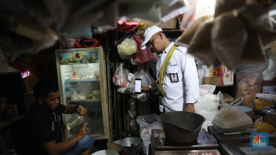 Karyawan Pasar Jaya mensosialisasikan kepada pedagang minyak di Pasar Kebayoran Lama, Jakarta, Senin (27/6/2022). Aplikasi PeduliLindungi saat ini menjadi syarat untuk membeli minyak goreng curah, sesuai dengan kebijakan pemerintah yang baru. (CNBC Indonesia/Muhammad Sabki)
