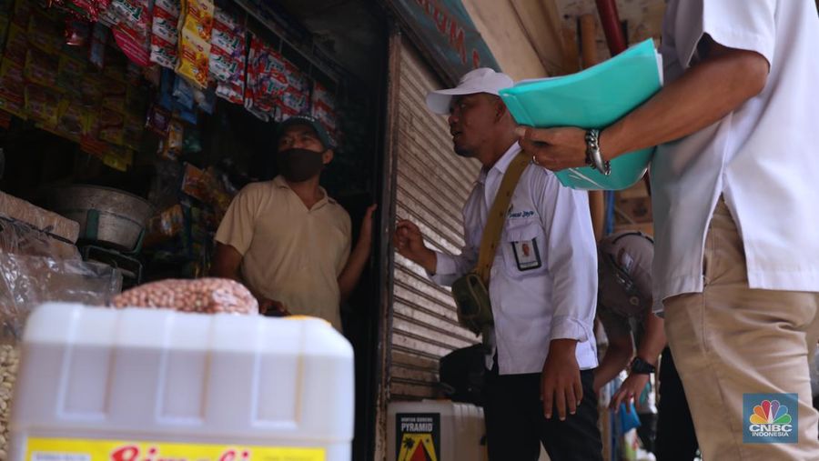 Karyawan Pasar Jaya mensosialisasikan kepada pedagang minyak di Pasar Kebayoran Lama, Jakarta, Senin (27/6/2022). Aplikasi PeduliLindungi saat ini menjadi syarat untuk membeli minyak goreng curah, sesuai dengan kebijakan pemerintah yang baru. (CNBC Indonesia/Muhammad Sabki)