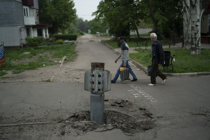 Seorang wanita berjalan melewati kawah cangkang di depan bangunan tempat tinggal yang rusak di kota Siversk, wilayah Donetsk. (AFP via Getty Images/ANATOLII STEPANOV) Seorang wanita berjalan melewati kawah cangkang di depan bangunan tempat tinggal yang rusak di kota Siversk, wilayah Donetsk. (AFP via Getty Images/ANATOLII STEPANOV)