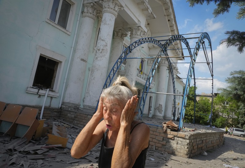 Seorang wanita berjalan melewati kawah cangkang di depan bangunan tempat tinggal yang rusak di kota Siversk, wilayah Donetsk. (AFP via Getty Images/ANATOLII STEPANOV) Seorang wanita berjalan melewati kawah cangkang di depan bangunan tempat tinggal yang rusak di kota Siversk, wilayah Donetsk. (AFP via Getty Images/ANATOLII STEPANOV)