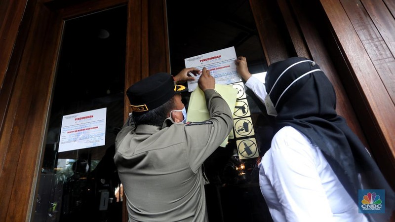 Petugas Satpol PP memasang spanduk penutupan Holywings Epicentrum, Jakarta, Selasa (28/6/2022). (CNBC Indonesia/Andrean Kristianto)