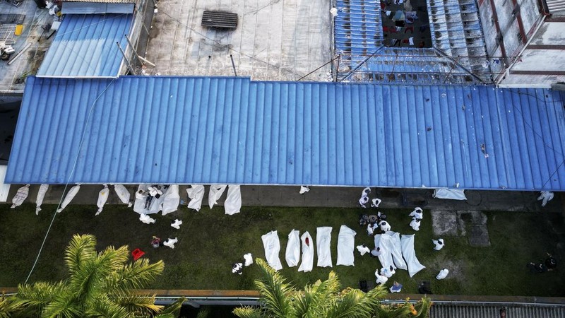 Penyelidik forensik berdiri di dekat kantong mayat setelah kebakaran mematikan di sebuah penjara di Tulua, Kolombia, Selasa, 28 Juni 2022. Pihak berwenang mengatakan setidaknya 51 orang tewas setelah kebakaran terjadi selama apa yang tampaknya merupakan percobaan kerusuhan Selasa pagi. (AP/Andres Quintero)