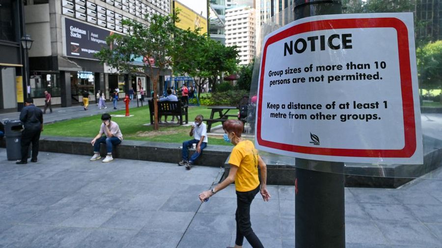 Pemberitahuan pembatasan jumlah kelompok untuk menghentikan penyebaran virus corona Covid-19 tergambar pada tiang lampu di Singapura. (AFP via Getty Images/ROSLAN RAHMAN)