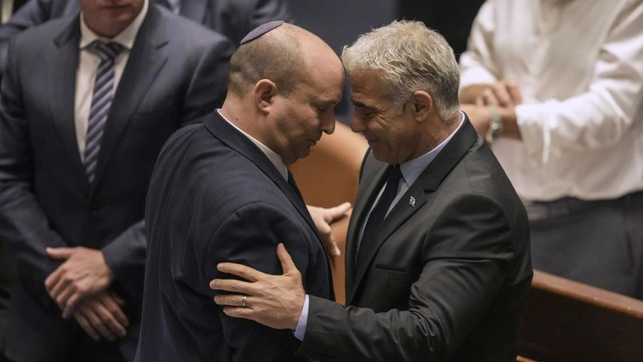 Perdana Menteri Israel Naftali Bennett, kiri, dan Menteri Luar Negeri Yair Lapid bereaksi setelah pemungutan suara pada RUU untuk membubarkan parlemen di Knesset, parlemen Israel, di Yerusalem, Kamis, 30 Juni 2022. (AP/Ariel Schalit)