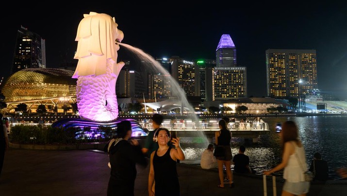 Warga berswafoto di patung Merlion Singapura ditengah lonjakan kasus Covid. (picture alliance via Getty Images)