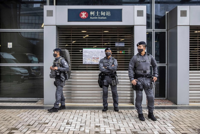 Polisi berjaga di dekat Stasiun West Kowloon di Hong Kong pada 30 Juni 2022, menjelang kedatangan Presiden China Xi Jinping di Hong Kong untuk merayakan ulang tahun ke-25 serah terima Hong Kong dari Inggris ke China yang berlangsung pada 1 Juli. (AFP via Getty Images/ISAAC LAWRENCE)