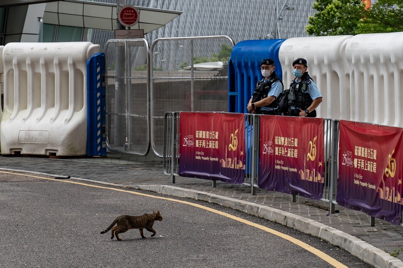 Polisi berjaga di dekat Stasiun West Kowloon di Hong Kong pada 30 Juni 2022, menjelang kedatangan Presiden China Xi Jinping di Hong Kong untuk merayakan ulang tahun ke-25 serah terima Hong Kong dari Inggris ke China yang berlangsung pada 1 Juli. (AFP via Getty Images/ISAAC LAWRENCE)