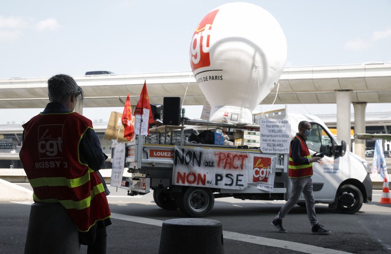 Aksi unjuk rasa pekerja di bandara Roissy-Charles-de-Gaulle di Paris, Prancis. Puluhan penerbangan di bandara tersibuk di Prancis dibatalkan sejak Jumat hingga Sabtu ini, 2 Juli 2022, yang dipicu perseteruan terkait masalah upah dan kondisi lingkungan kerja. Unjuk rasa ini terjadi di kalangan petugas pemadam kebakaran area bandara. (AP/Thomas Padilla)