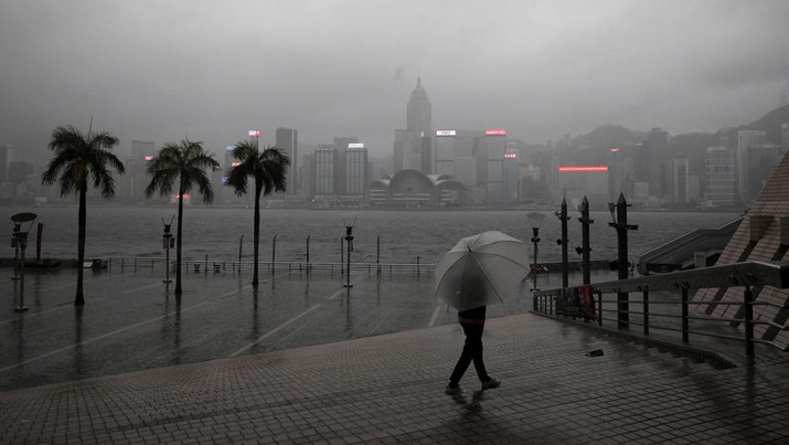 Seseorang yang memegang payung berjalan di tengah hujan di tepi pantai, di tengah peringatan topan pada peringatan 25 tahun penyerahan bekas jajahan Inggris ke pemerintahan China, di Hong Kong. (REUTERS/PAUL YEUNG)