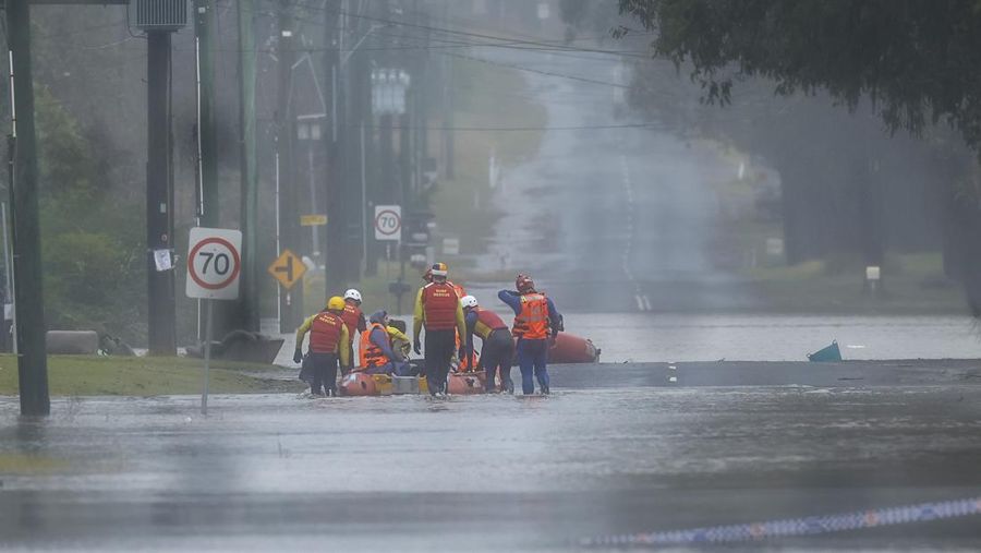 Keluarga dievakuasi oleh pekerja Layanan Darurat Negara karena meningkatnya air banjir di Bligh Park, Sydney, Australia, Senin (4/7/2022). Ribuan penduduk terpaksa meninggalkan rumah mereka semalaman dan sejumlah perintah evakuasi diberlakukan di seluruh Sydney saat hujan lebat dan banjir terus berlanjut. (Photo by Jenny Evans/Getty Images)