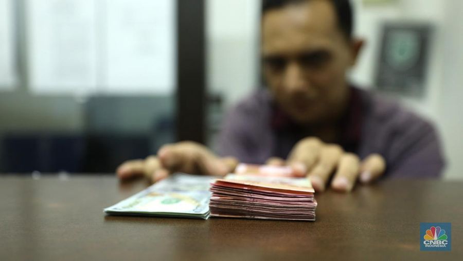 Pekerja memperlihatkan uang dolar di salah satu gerai money changer di Jakarta, Senin (4/7/2022).  (CNBC Indonesia/ Tri Susilo)