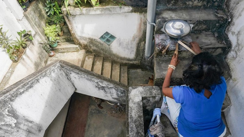 Warga memasak makanan dengan tungku kayu di luar rumah susunnya di Kolombo, Sri Lanka, Senin (4/7/2022). Sri Lanka kehabisan bahan bakar bensin dan diesel usai pengiriman pasokan ditunda tanpa kepastian. (Photo by Thilina Kaluthotage/NurPhoto via Getty Images)