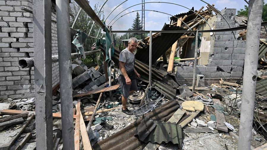 Seorang penduduk berjalan di antara puing-puing di samping sebuah rumah yang hancur sehari setelah serangan roket Rusia di pasar lokal Sloviansk, Ukraina, Senin (4/7/2022). Sedikitnya enam orang dilaporkan tewas setelah kota Sloviansk di wilayah Ukraina bagian timur dihantam gempuran kuat Rusia yang diduga menggunakan peluncur roket MLRS. (Photo by GENYA SAVILOV/AFP via Getty Images)