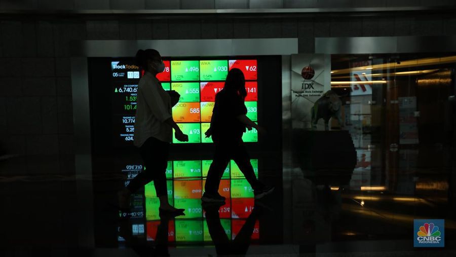 Karyawan melintas di depam layar digital pergerakan Indeks Harga Saham Gabungan (IHSG) di Bursa Efek Indonesia, Jakarta, Selasa (5/7/2022). (CNBC Indonesia/ Tri Susilo)