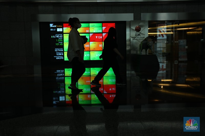 Karyawan melintas di depan layar digital pergerakan Indeks Harga Saham Gabungan (IHSG) di Bursa Efek Indonesia, Jakarta, Selasa (5/7/2022). (CNBC Indonesia/ Tri Susilo)