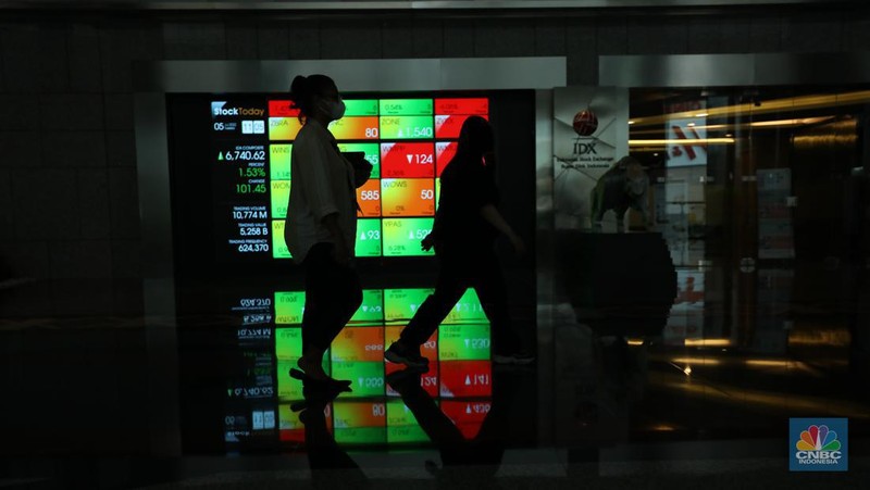 Karyawan melintas di depan layar digital pergerakan Indeks Harga Saham Gabungan (IHSG) di Bursa Efek Indonesia, Jakarta, Selasa (5/7/2022). (CNBC Indonesia/ Tri Susilo)