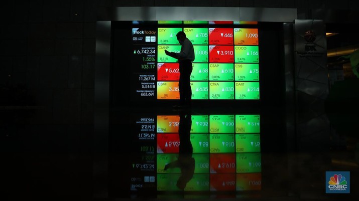 Karyawan melintas di depam layar digital pergerakan Indeks Harga Saham Gabungan (IHSG) di Bursa Efek Indonesia, Jakarta, Selasa (5/7/2022). (CNBC Indonesia/ Tri Susilo)