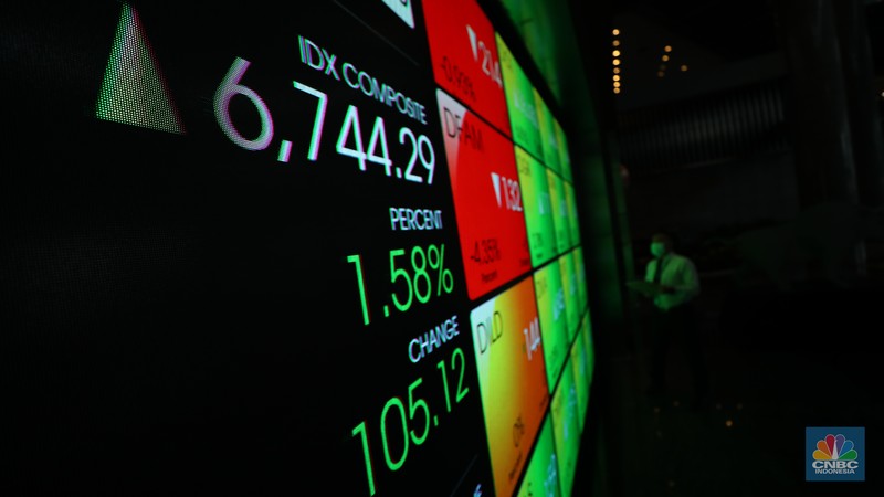 Karyawan melintas di depan layar digital pergerakan Indeks Harga Saham Gabungan (IHSG) di Bursa Efek Indonesia, Jakarta, Selasa (5/7/2022). (CNBC Indonesia/ Tri Susilo)