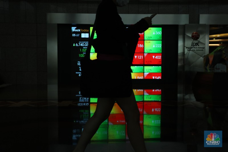 Karyawan melintas di depan layar digital pergerakan Indeks Harga Saham Gabungan (IHSG) di Bursa Efek Indonesia, Jakarta, Selasa (5/7/2022). (CNBC Indonesia/ Tri Susilo)