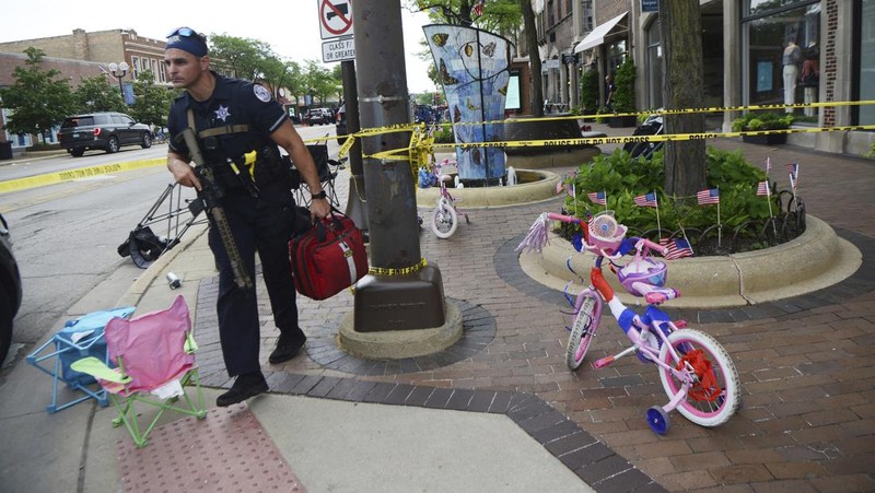 Polisi memeriksa sebuah bangunan setelah tembakan meletus di rute Parade Hari Kemerdekaan Amerika Serikat di Highland Park, Chicago, Illinois, Amerika Serikat, Senin (4/7/2022). Sebanyak 6 orang dilaporkan tewas akibat penembakan tersebut. (AP Photo/Nam Y. Huh)