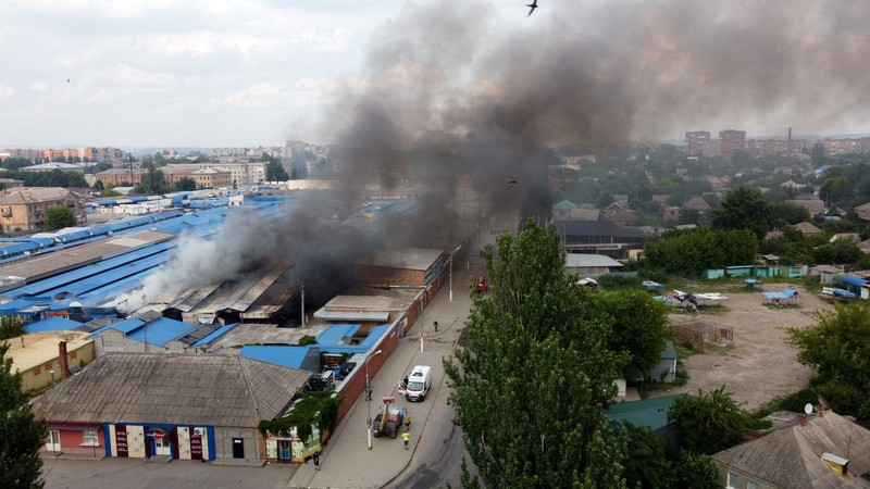 Foto udara menunjukkan asap mengepul dari pasar akibat pemboman yang dilancarkan oleh Rusia di Ukraina berlanjut di Sloviansk, wilayah Donetsk, Ukraina, Selasa (5/7/2022). Otoritas Ukraina mengungkapkan sebanyak 2 orang tewas dan 7 warga lainnya terluka akibat serangan itu. (Photo by MIGUEL MEDINA/AFP via Getty Images)