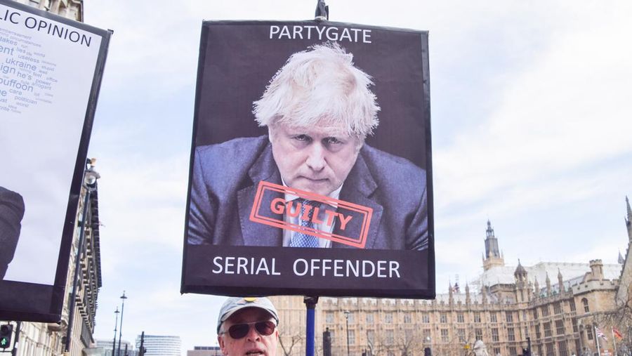 Seorang pengunjuk rasa memegang poster yang menyebut Boris Johnson 