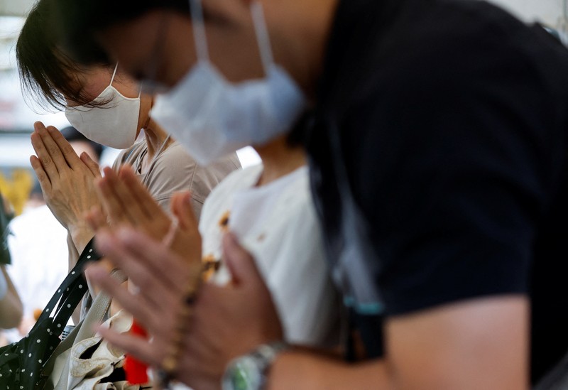 Japan Abe Shot People pray at a makeshift memorial at the scene where the former Prime Minister Shinzo Abe was shot while delivering his speech to support the Liberal Democratic Party's candidate during an election campaign in Nara, Friday, July 8, 2022. Abe, a divisive arch-conservative and one of his nation's most powerful and influential figures, has died after being shot during a campaign speech Friday in western Japan, hospital officials said.(Kyodo News via AP)