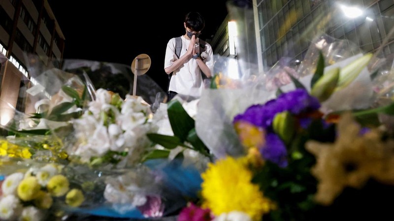 People pray at a makeshift memorial at the scene where the former Prime Minister Shinzo Abe was shot while delivering his speech to support the Liberal Democratic Party's candidate during an election campaign in Nara, Friday, July 8, 2022.  Abe, a divisive arch-conservative and one of his nation's most powerful and influential figures, has died after being shot during a campaign speech Friday in western Japan, hospital officials said.(Kyodo News via AP)