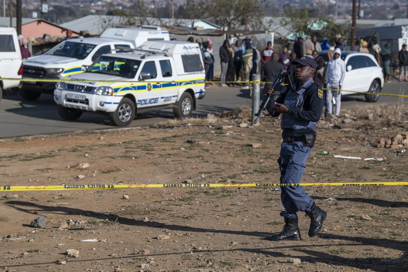 1241816651 SOWETO, SOUTH AFRICA - JULY 10: A woman reacts as securtiy forces and forensic service inspect the scene of a mass shooting in Soweto, South Africa, on July 10, 2022. Fourteen people have been killed in a mass shooting at a bar in Soweto township near Johannesburg, police said Sunday. (Photo by Ihsaan Haffejee/Anadolu Agency via Getty Images)