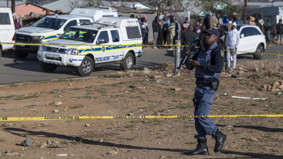 SOWETO, SOUTH AFRICA - JULY 10:  A woman reacts as securtiy forces and forensic service inspect the scene of a mass shooting in Soweto, South Africa, on July 10, 2022. Fourteen people have been killed in a mass shooting at a bar in Soweto township near Johannesburg, police said Sunday. (Photo by Ihsaan Haffejee/Anadolu Agency via Getty Images)