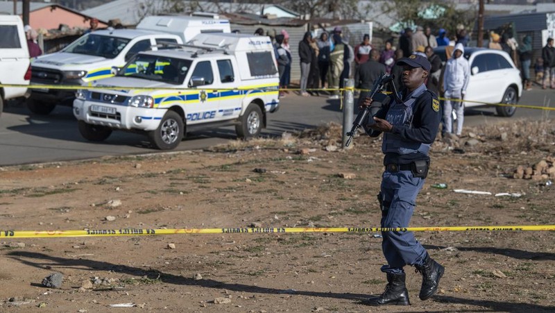SOWETO, SOUTH AFRICA - JULY 10:  A woman reacts as securtiy forces and forensic service inspect the scene of a mass shooting in Soweto, South Africa, on July 10, 2022. Fourteen people have been killed in a mass shooting at a bar in Soweto township near Johannesburg, police said Sunday. (Photo by Ihsaan Haffejee/Anadolu Agency via Getty Images)