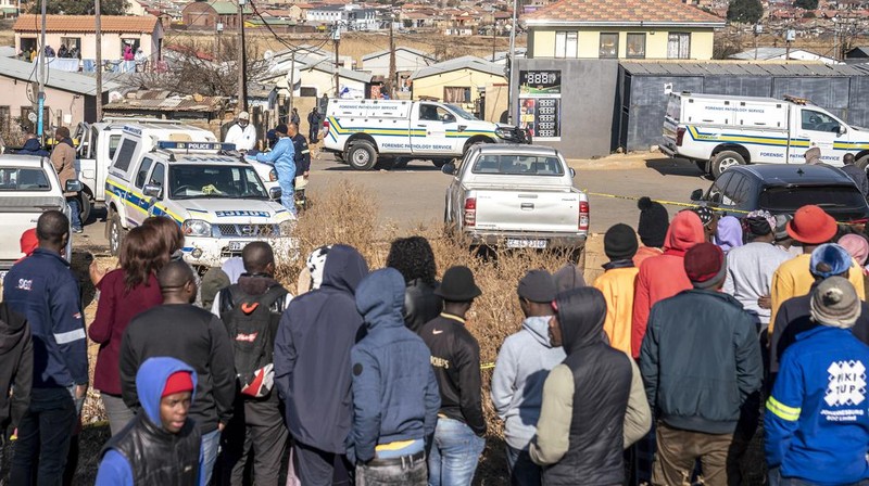 SOWETO, SOUTH AFRICA - JULY 10:  A woman reacts as securtiy forces and forensic service inspect the scene of a mass shooting in Soweto, South Africa, on July 10, 2022. Fourteen people have been killed in a mass shooting at a bar in Soweto township near Johannesburg, police said Sunday. (Photo by Ihsaan Haffejee/Anadolu Agency via Getty Images)