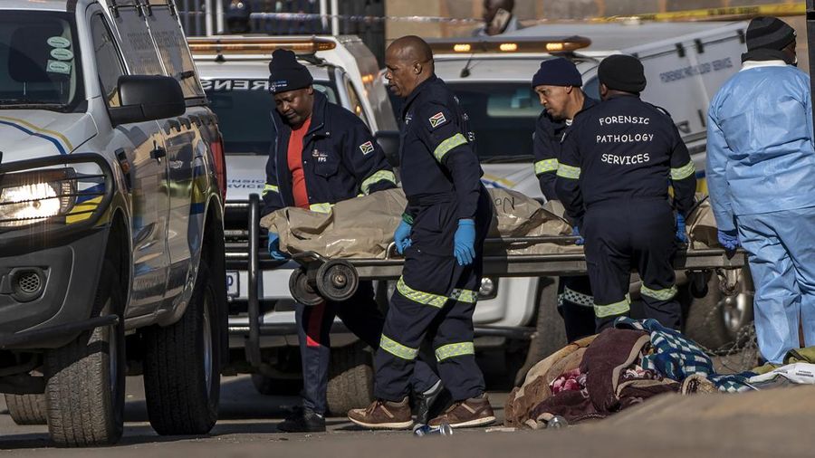 SOWETO, SOUTH AFRICA - JULY 10:  A woman reacts as securtiy forces and forensic service inspect the scene of a mass shooting in Soweto, South Africa, on July 10, 2022. Fourteen people have been killed in a mass shooting at a bar in Soweto township near Johannesburg, police said Sunday. (Photo by Ihsaan Haffejee/Anadolu Agency via Getty Images)