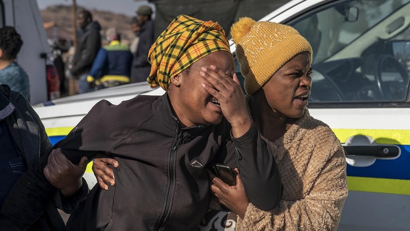 SOWETO, SOUTH AFRICA - JULY 10:  A woman reacts as securtiy forces and forensic service inspect the scene of a mass shooting in Soweto, South Africa, on July 10, 2022. Fourteen people have been killed in a mass shooting at a bar in Soweto township near Johannesburg, police said Sunday. (Photo by Ihsaan Haffejee/Anadolu Agency via Getty Images)