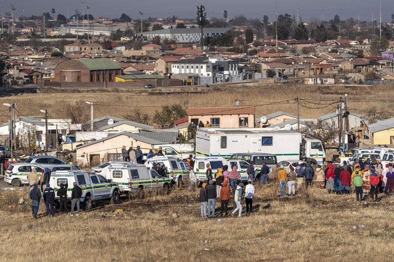 1241816651 SOWETO, SOUTH AFRICA - JULY 10: A woman reacts as securtiy forces and forensic service inspect the scene of a mass shooting in Soweto, South Africa, on July 10, 2022. Fourteen people have been killed in a mass shooting at a bar in Soweto township near Johannesburg, police said Sunday. (Photo by Ihsaan Haffejee/Anadolu Agency via Getty Images)